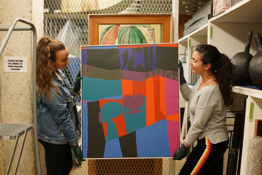 students holding a piece of art from the permanent collection at FSU museum of fine arts